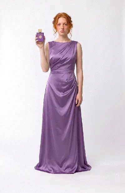 Model in a lilac dress presenting a fragrance